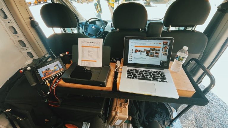 A mobile workstation set up in a van with a laptop, printer, and camera gear, showcasing on-site field documentation for Caterpillar.